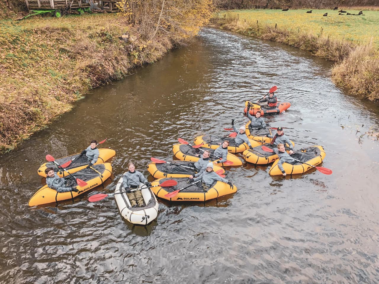 Een vrolijke groep in oranje pakjes op een rustige rivier midden in de natuur in de Ardennen.