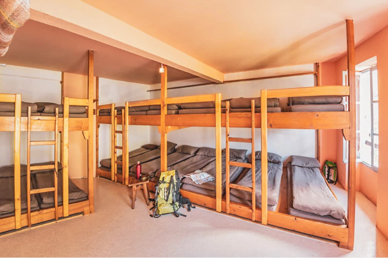 Chambre lumineuse avec lits superposés en bois, idéale pour se reposer après l'aventure en montagne.