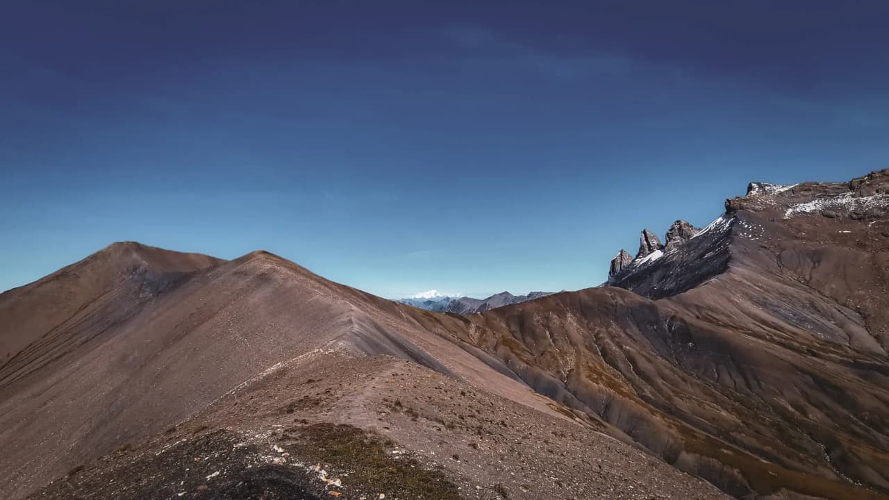 Panorama majestueux sur les sommets et vallées arides du plateau montagneux, ciel bleu éclatant.