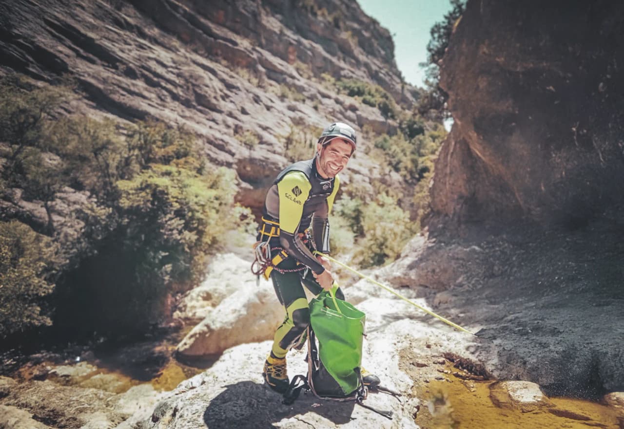 An adventurer in canyoning gear strikes a pose.