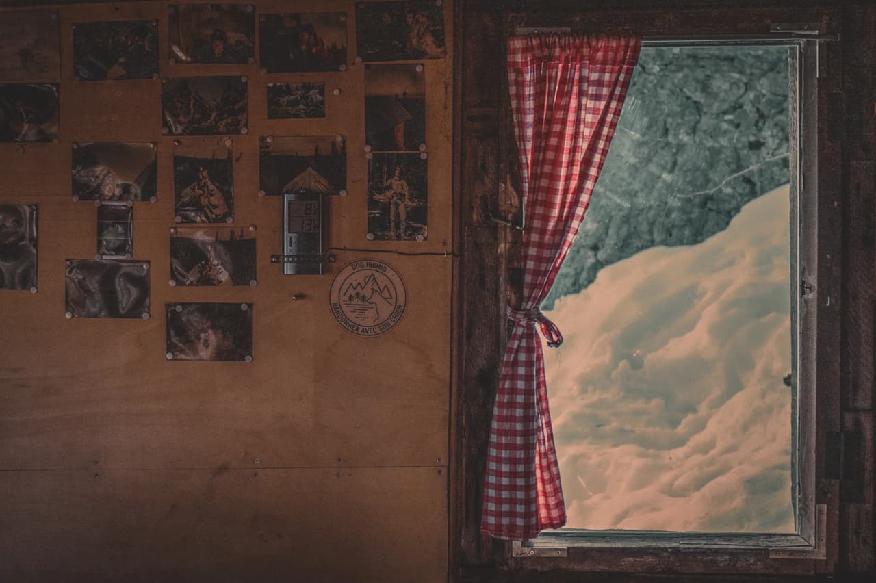 Intérieur chaleureux avec fenêtre sur un paysage enneigé, invitation à l'aventure hivernale.