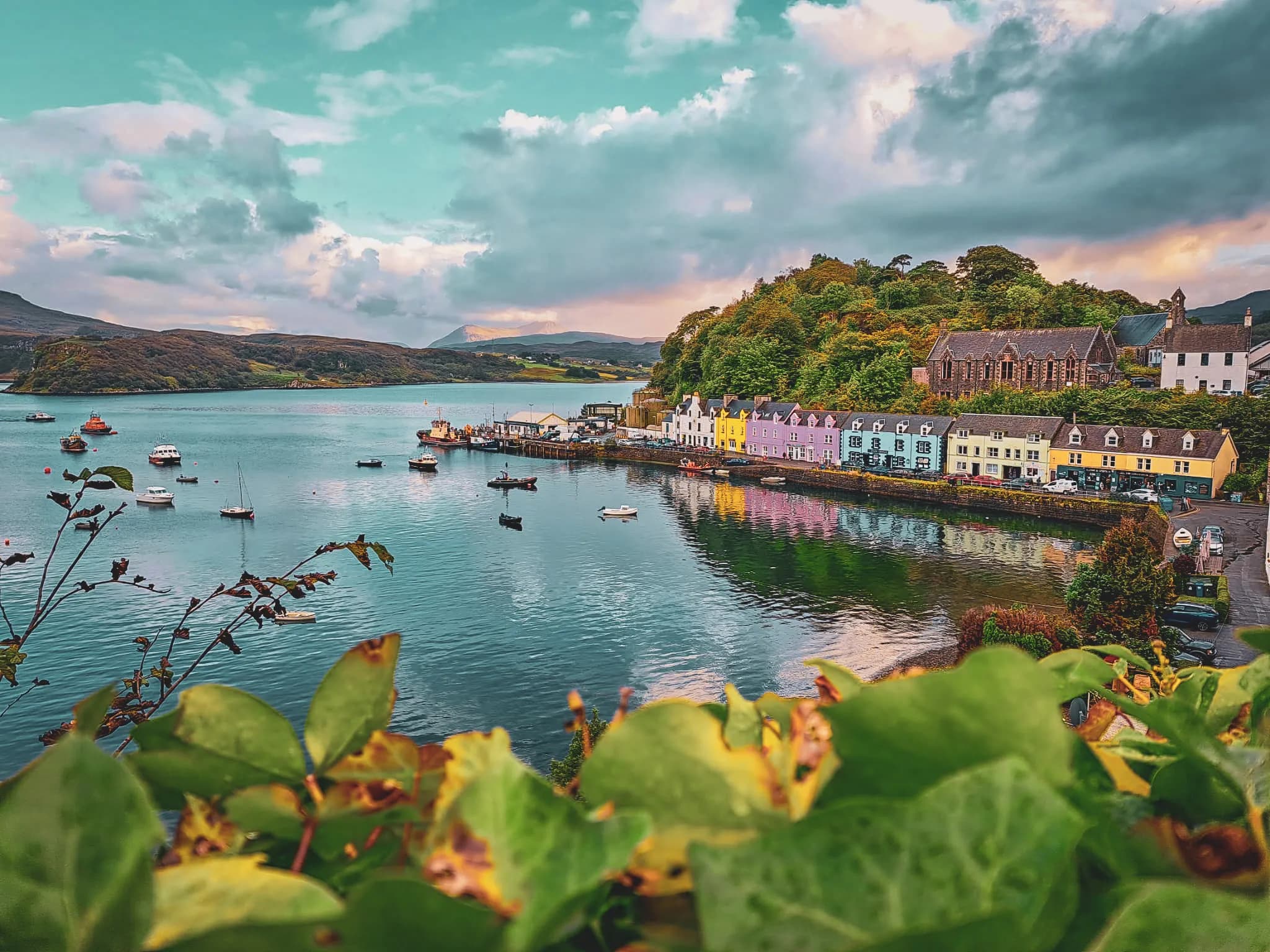 Colourful harbour on the Isle of Skye, with moored boats and mountains in the background.