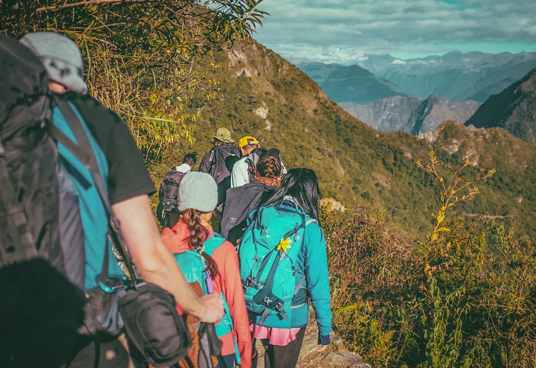 A group of hikers on a mountain trail, surrounded by Alpine scenery.