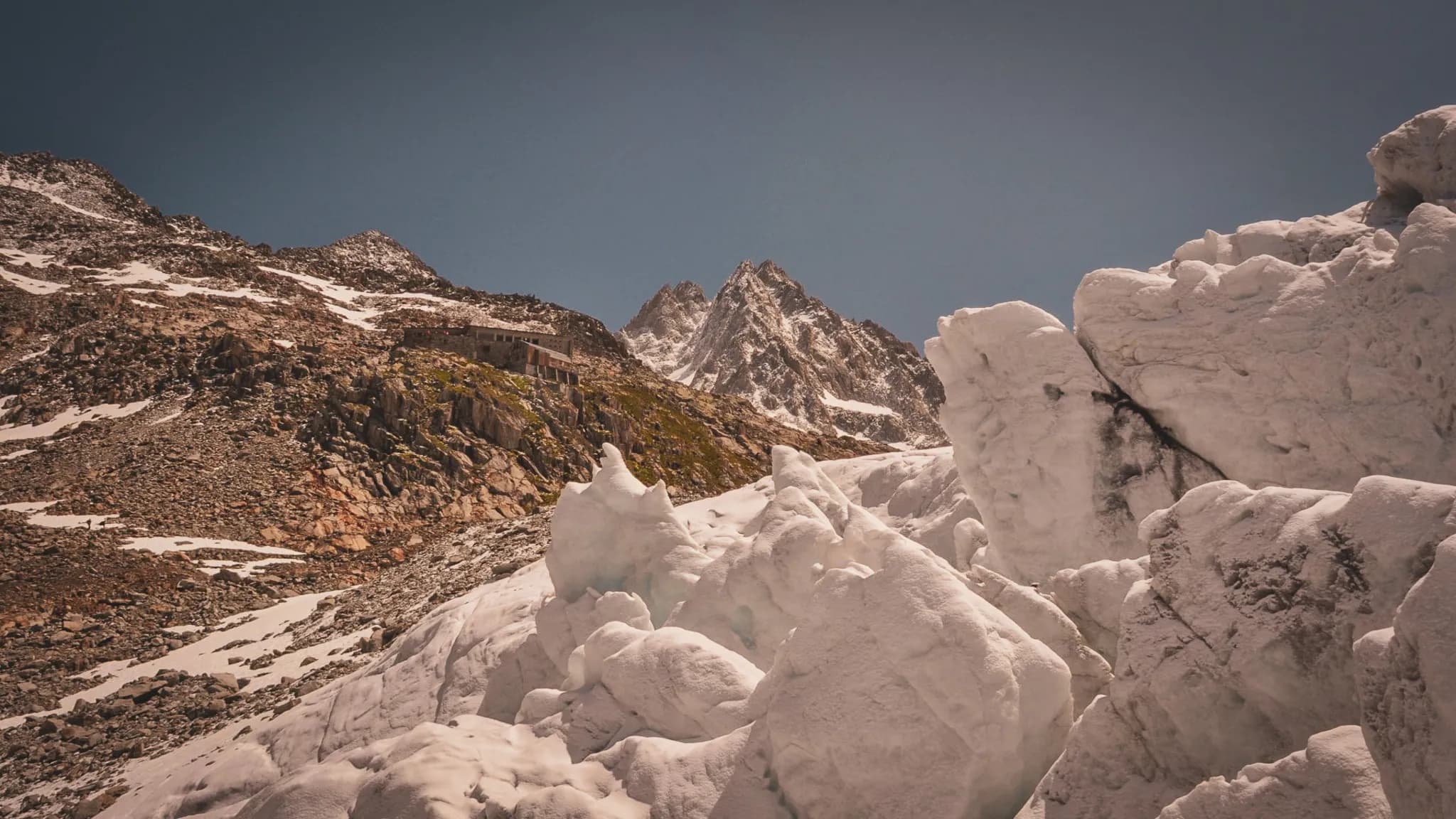 Majestic Alpine scenery, glistening glaciers under a blue sky, an invitation to adventure.