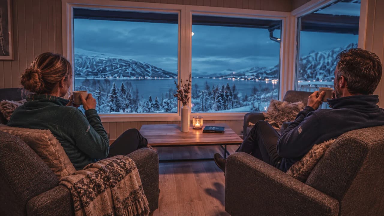 Een stel ontspant zich met een warm drankje en geniet van het vredige, besneeuwde landschap in Tromsø.