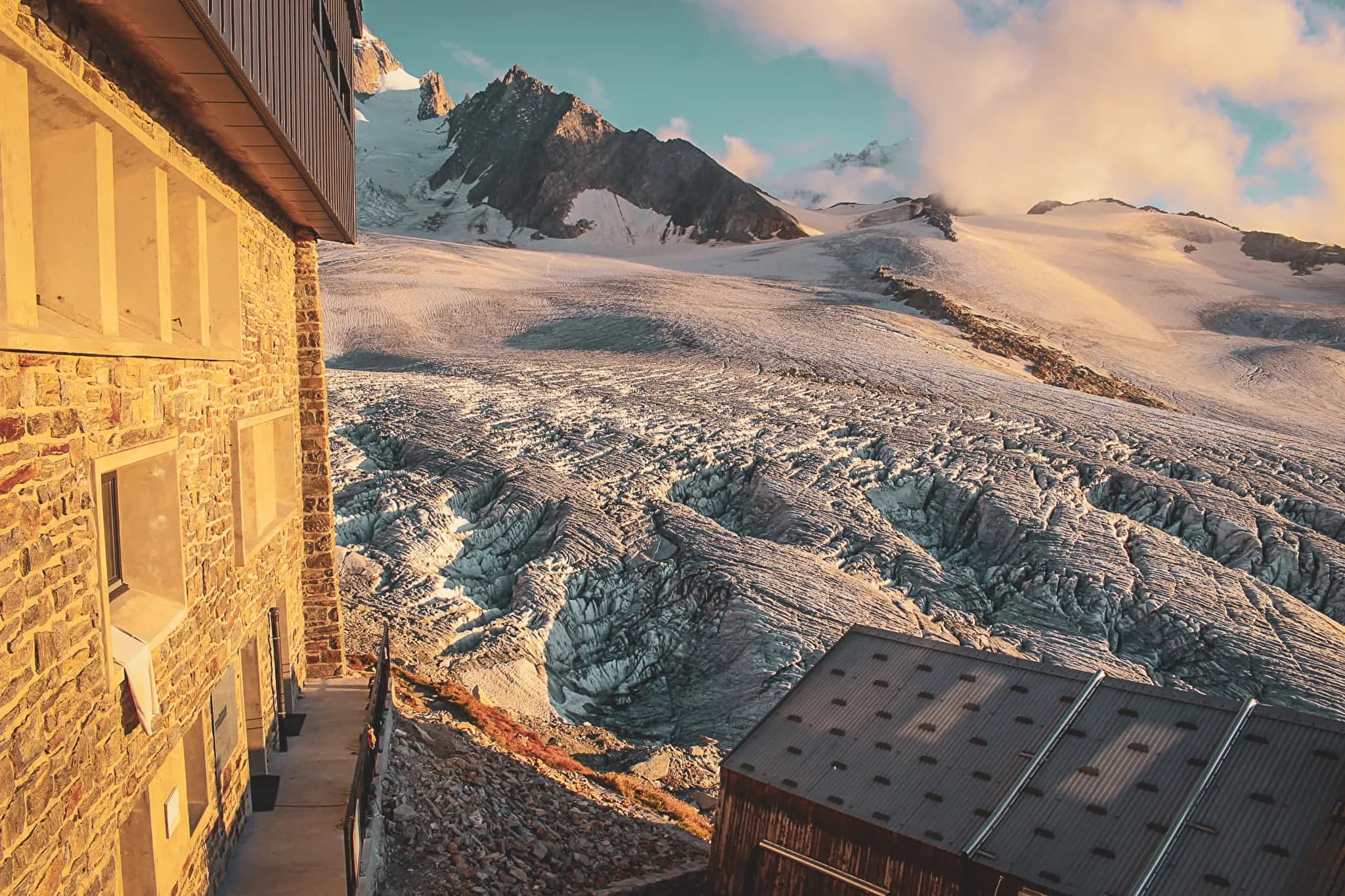 Vue majestueuse sur un glacier des Alpes, avec un chalet accueillant au premier plan.