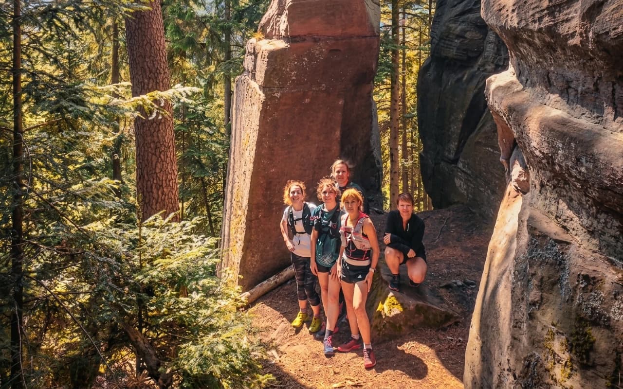 Een groep lachende wandelaars in een bos, omringd door majestueuze rotsen.