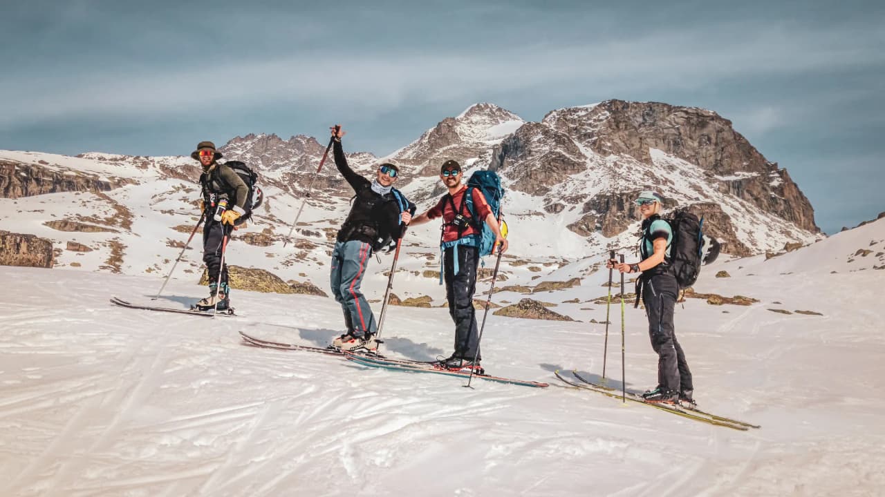 Four skiers ascending Grand Paradis, with snow-capped peaks in the background.
