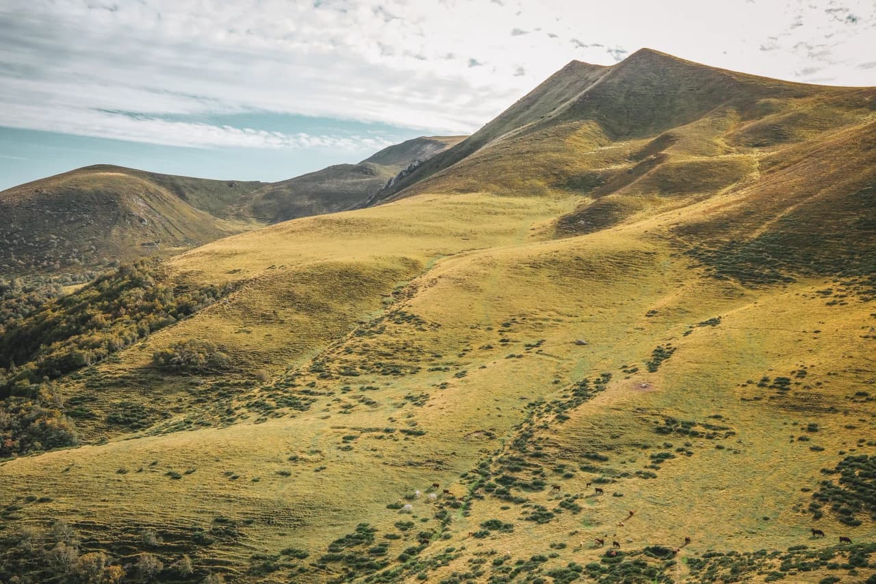 The golden green hills of the Auvergne, surrounded by blue skies, are an invitation to adventure.