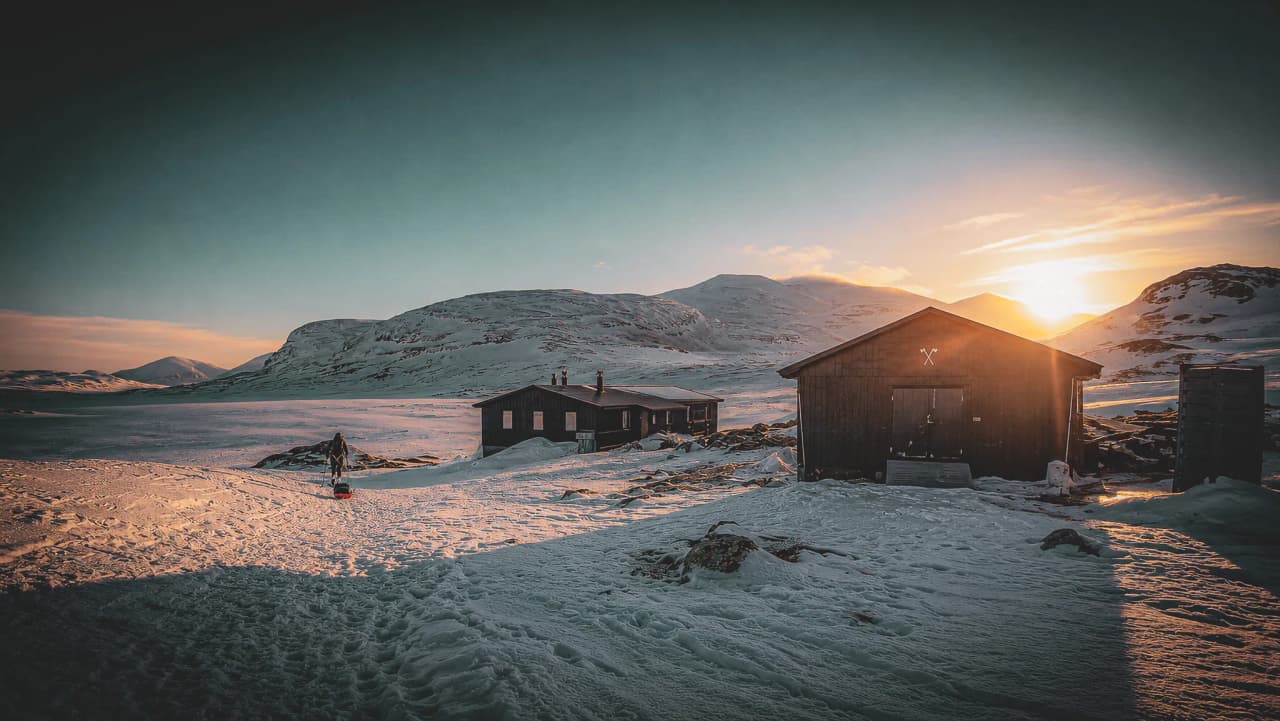 Een majestueus alpenlandschap bij zonsondergang, afgelegen Berghutten omringd door ongerepte sneeuw.