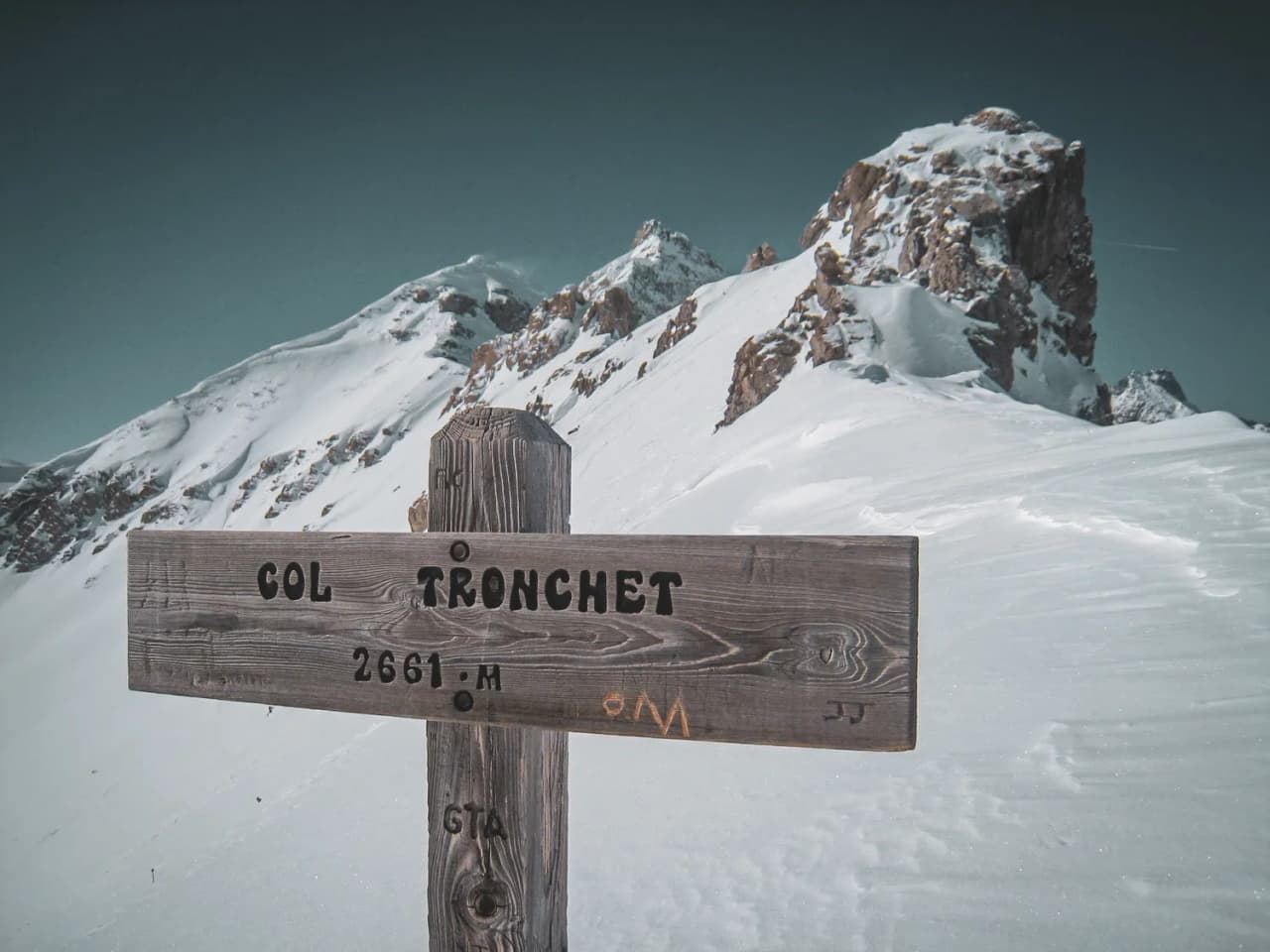 Panneau indicatif au Col Tronchet, entouré de majestueuses montagnes enneigées du Queyras.