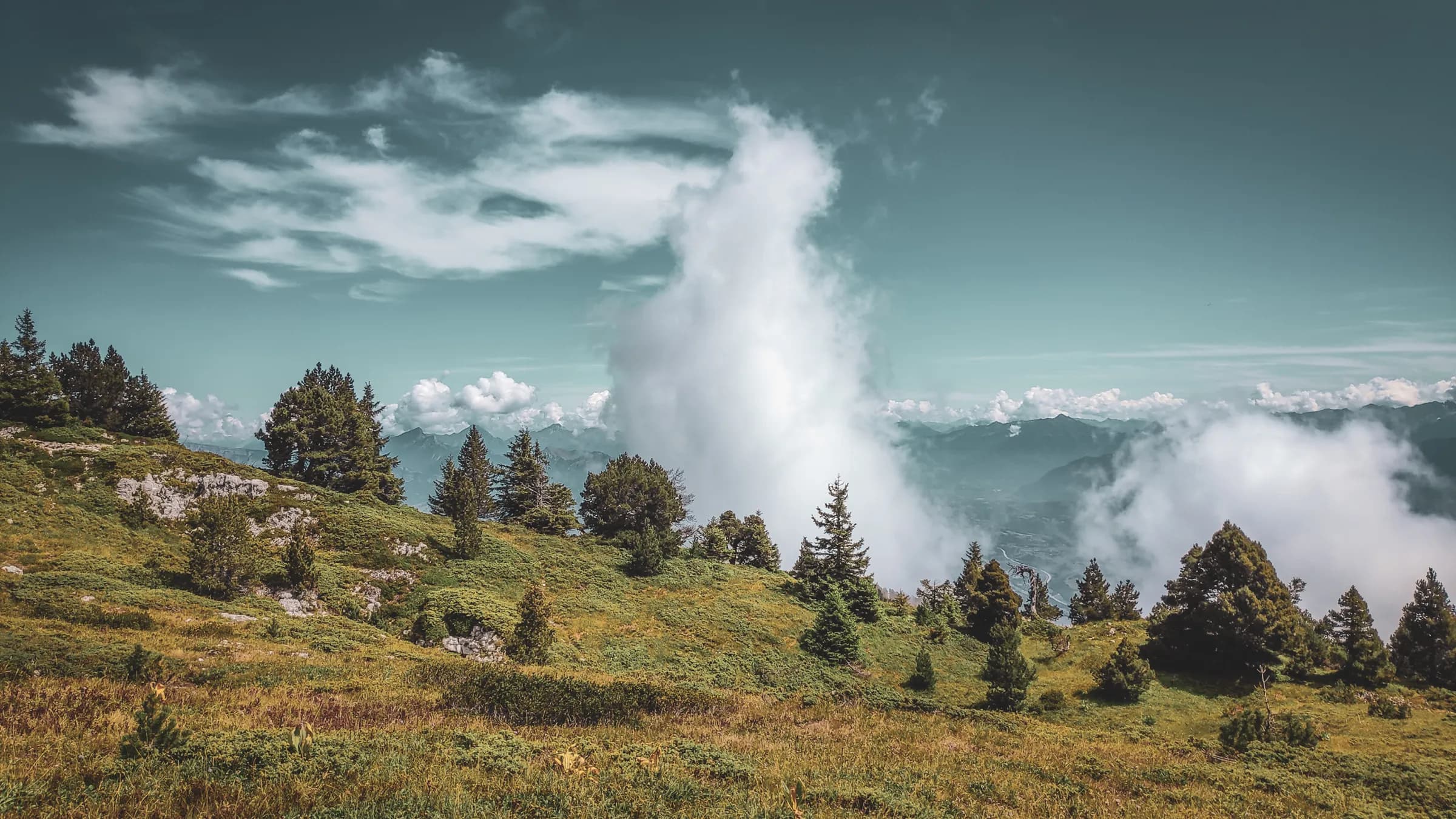 Paysage montagneux verdoyant avec des nuages flottants, invitant à l'exploration en Chartreuse.