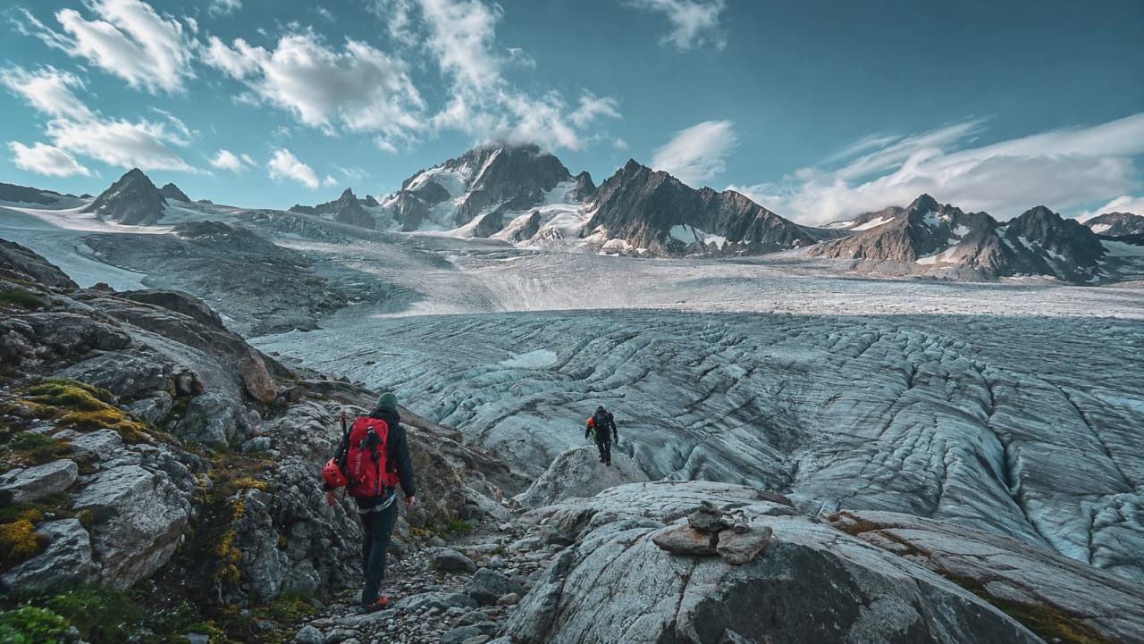 Deux alpinistes explorent un glacier majestueux au milieu des sommets alpins scintillants.