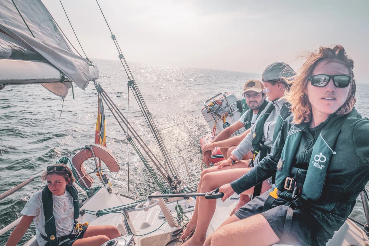 Een zeilteam op een boot, varend over de sprankelende wateren van Belle-Île.