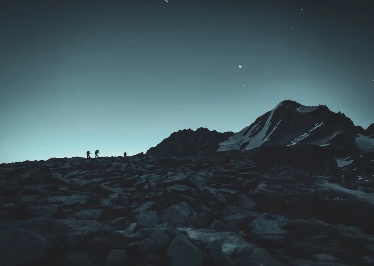 Mountaineers silhouetted against the majestic summit at sunrise, a serene and adventurous atmosphere.