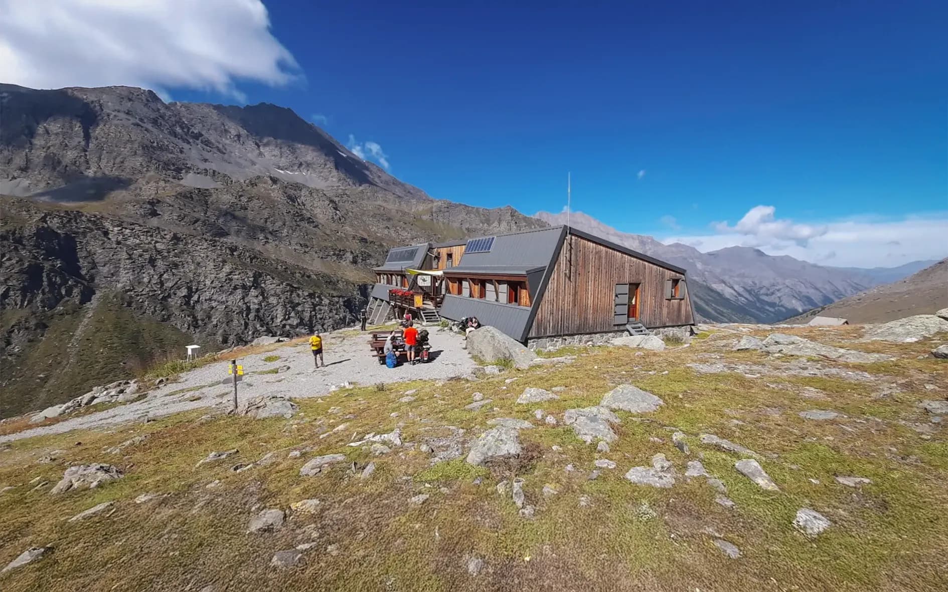 Mountain hut in the heart of the Alps, surrounded by majestic scenery and brilliant blue skies.