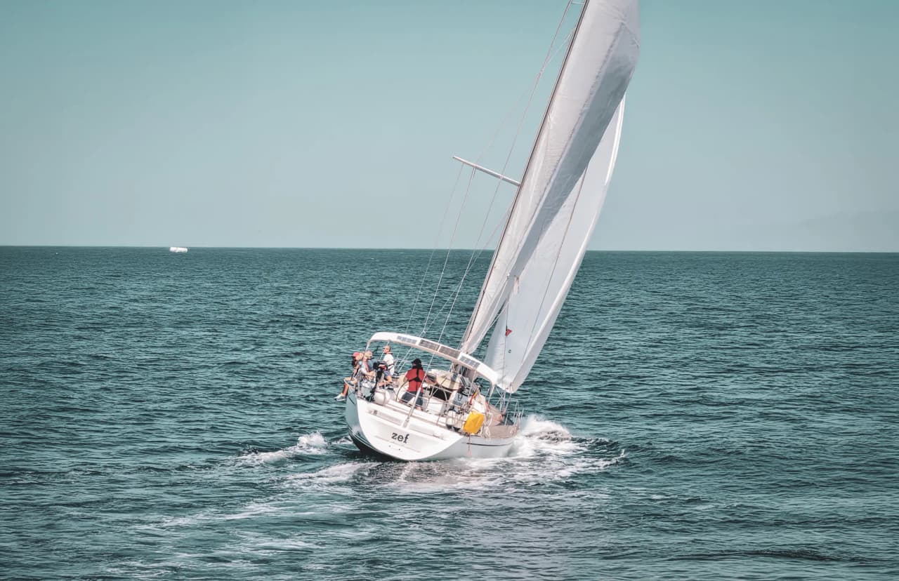 Voilier naviguant en mer turquoise, entouré de paysages bretons splendides.