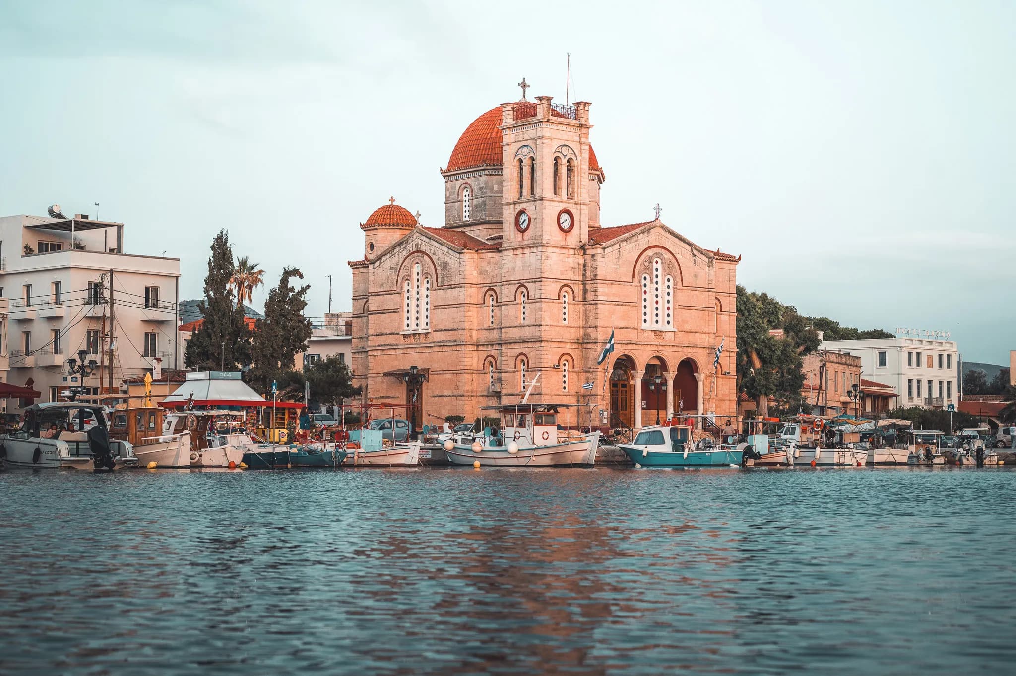 Église pittoresque au bord de l'eau, entourée de charmants bateaux et d'une ambiance méditerranéenne.