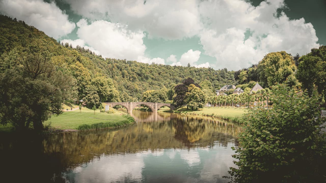 Stenen brug over de rivier de Semois, omgeven door weelderig groen en vredige heuvels.