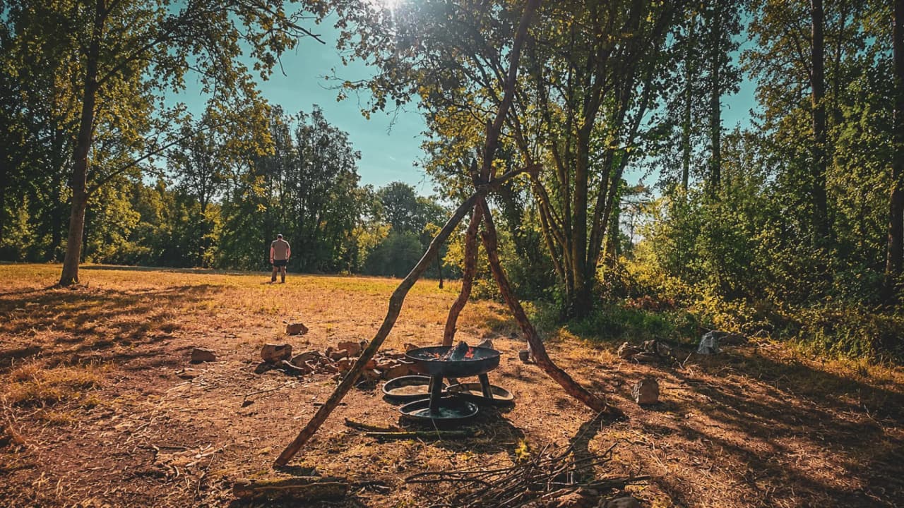 Un camp de survie en Ardenne, feu de camp sous les arbres, aventure nature et ressourcement.