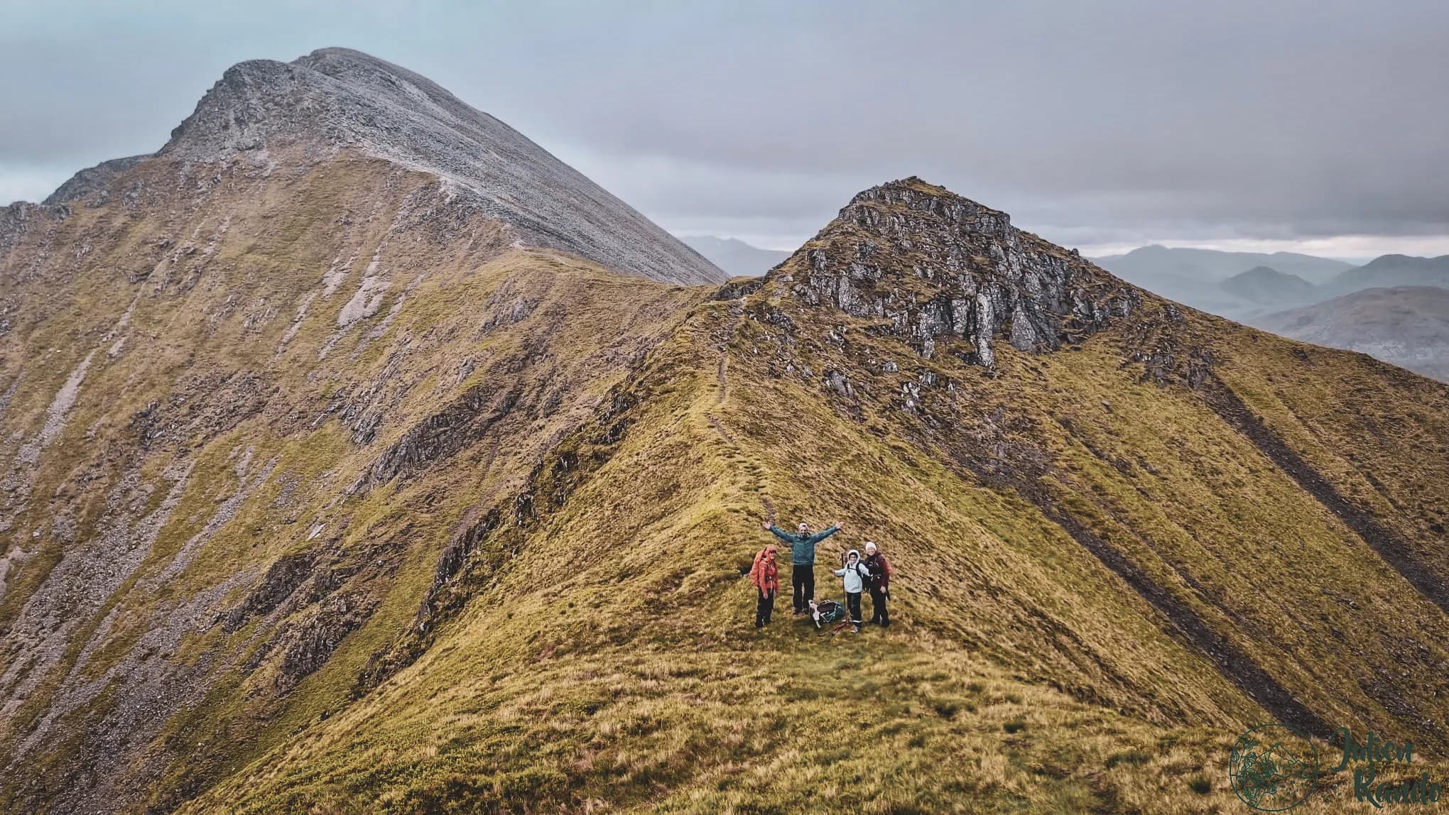 A group of adventurers on a summit in the Scottish Highlands, surrounded by majestic valleys.