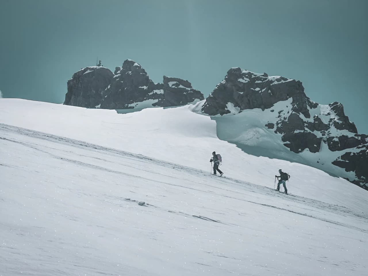 Alpinists climbing a snow-covered slope, surrounded by the majestic mountains of the Alps.