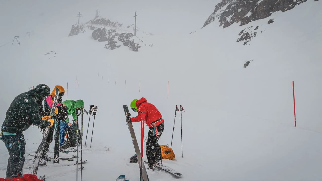 A group of mountaineers in the snow on a glacier, skis in hand, ready for adventure.