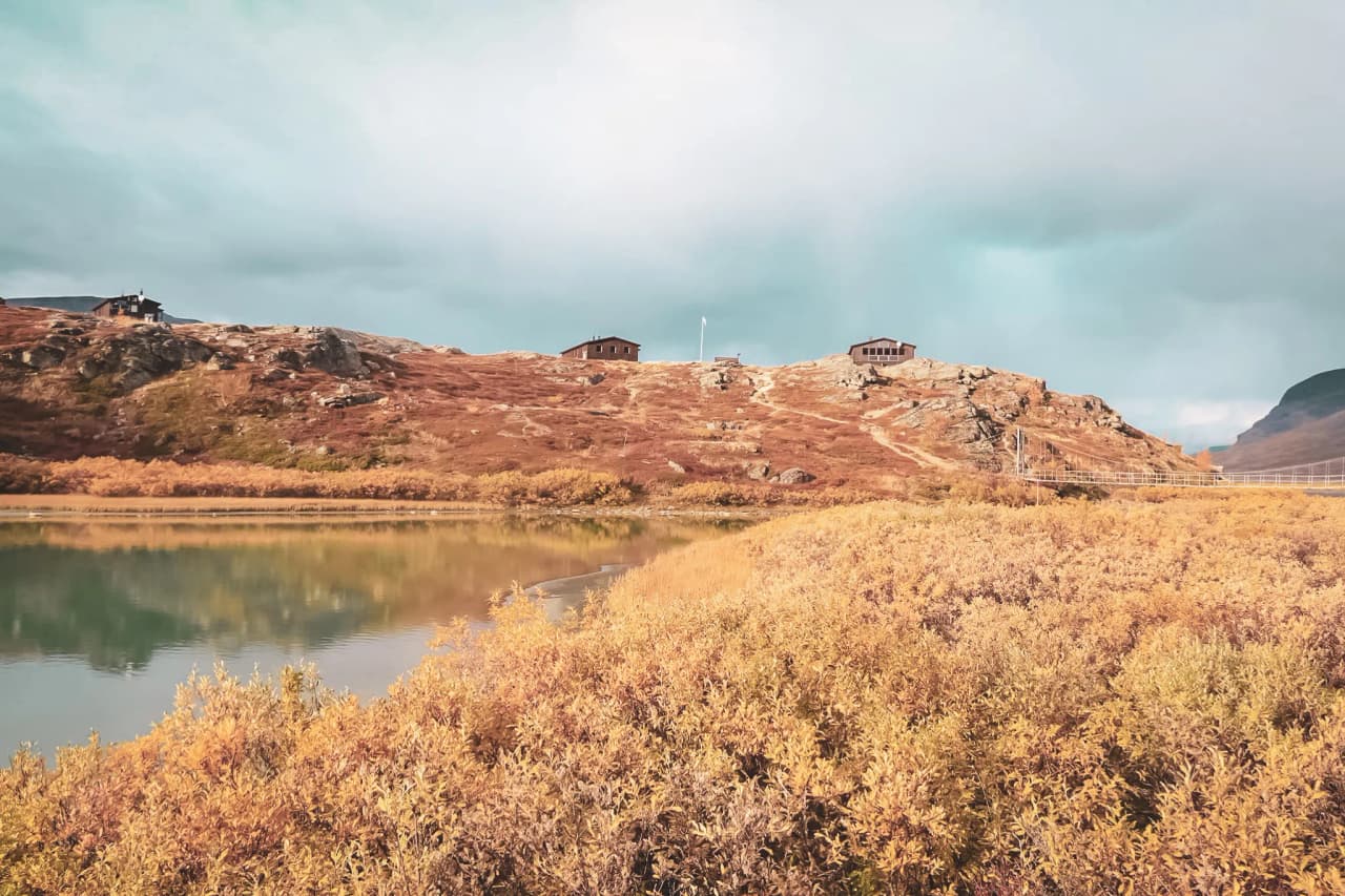 Autumn landscape with sparkling streams and picturesque huts in Lapland.