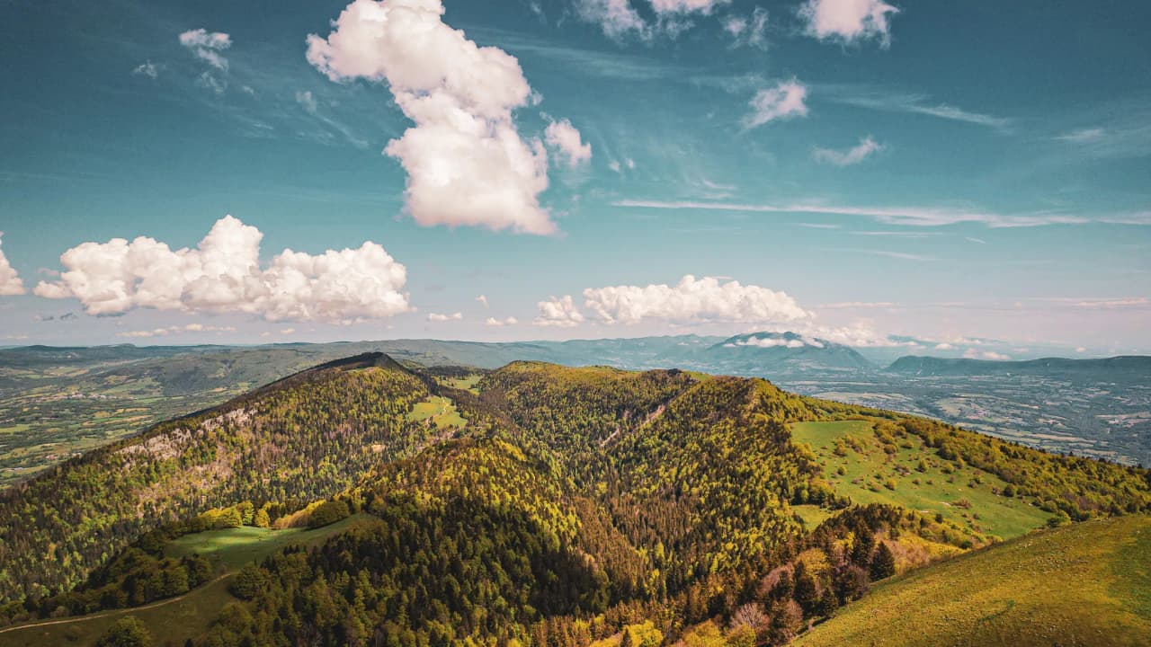 Green panoramas of the Jura mountains, blue skies dotted with clouds, an invitation to get away from it all.