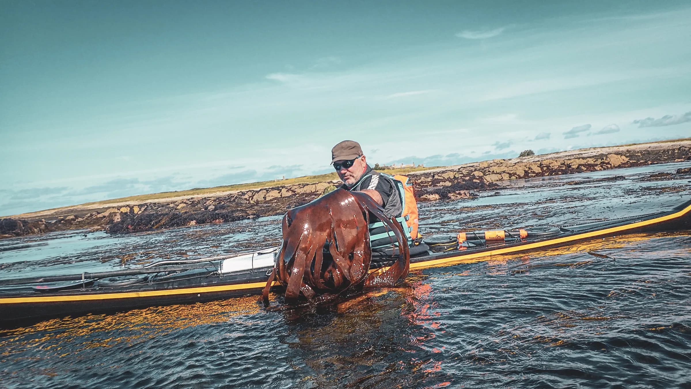 A kayaker holding a large octopus, surrounded by the peaceful waters of the Molène archipelago.