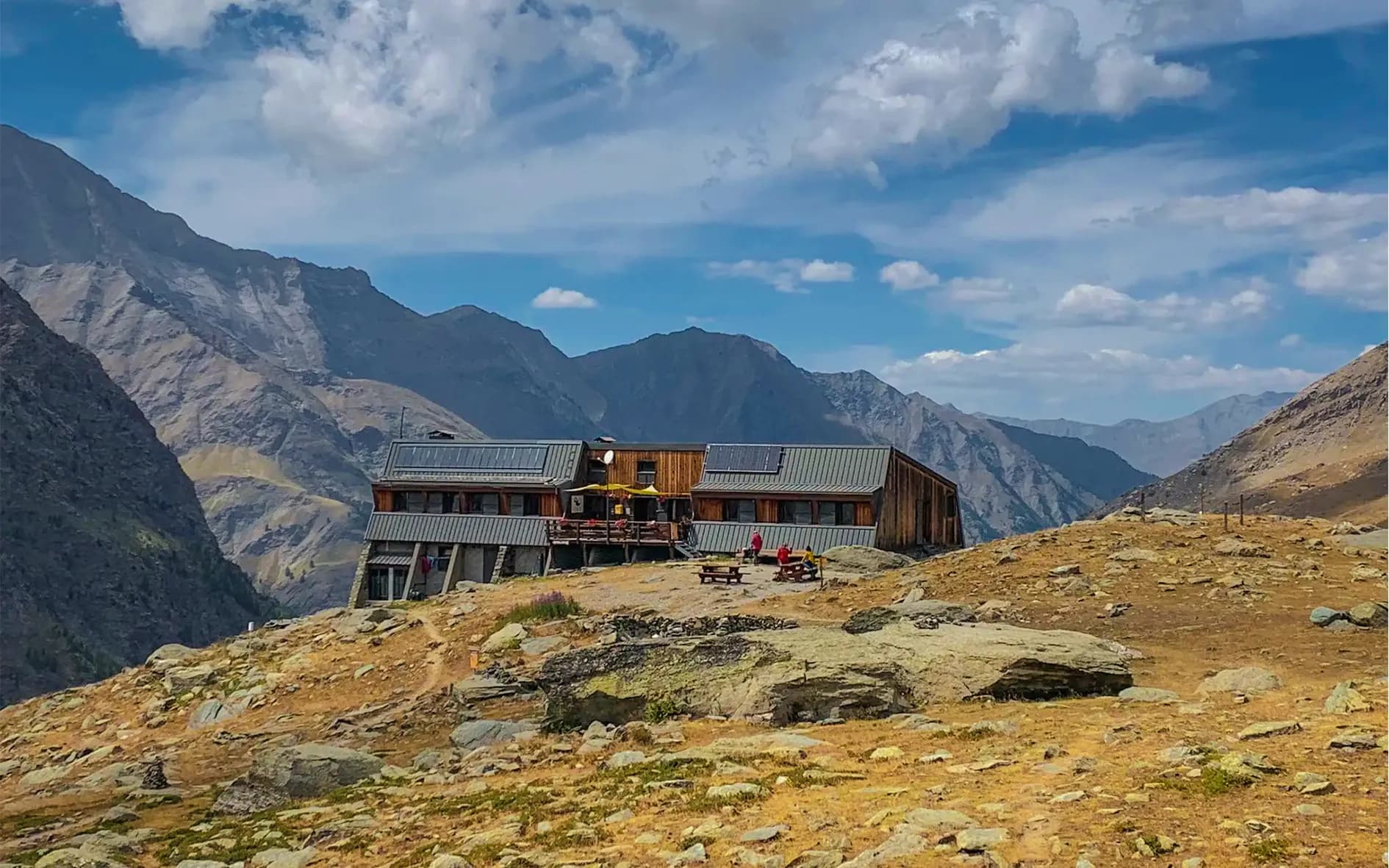 A welcoming Mountain hut on the edge of Mont Viso, with majestic mountains in the background.