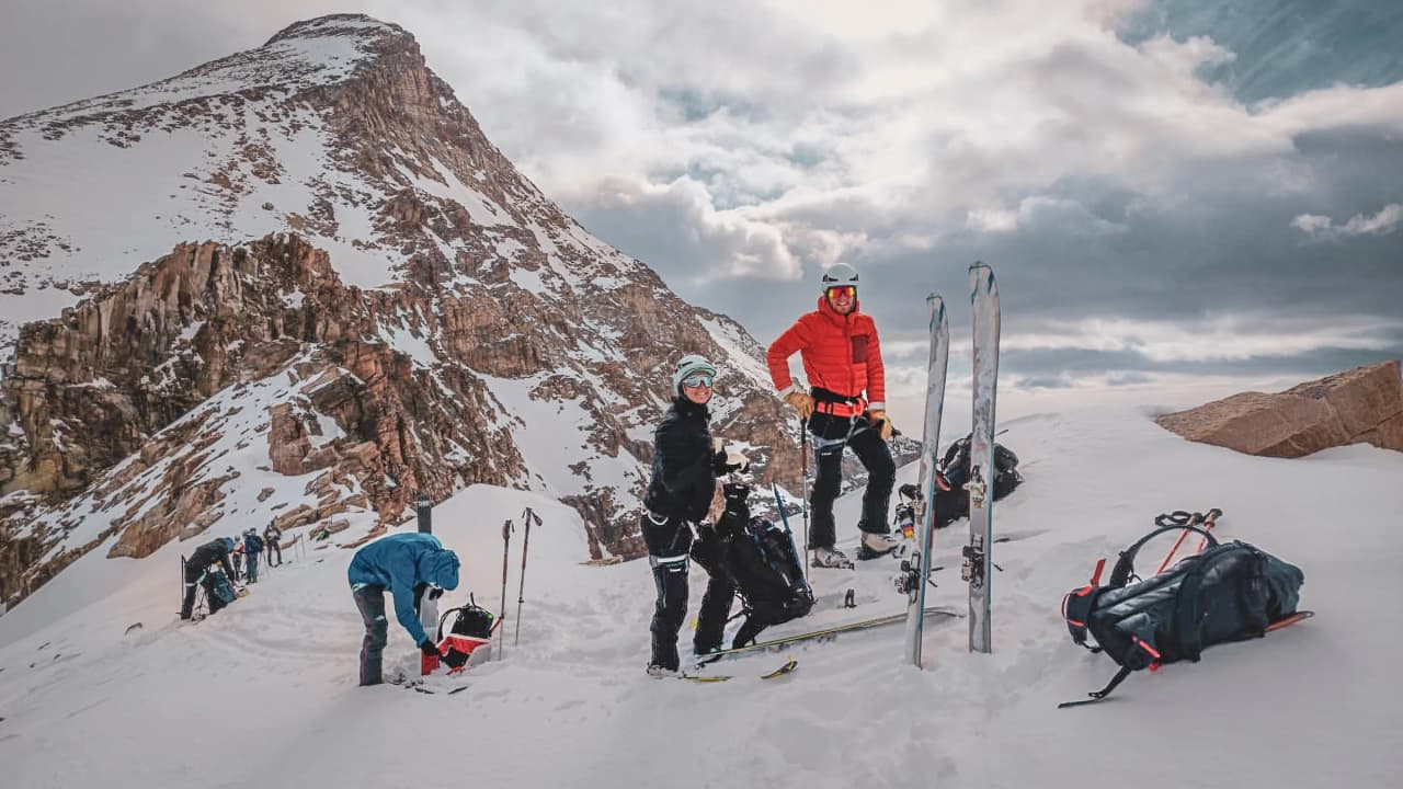 Group of adventurers skiing on the snow, with majestic mountains in the background.