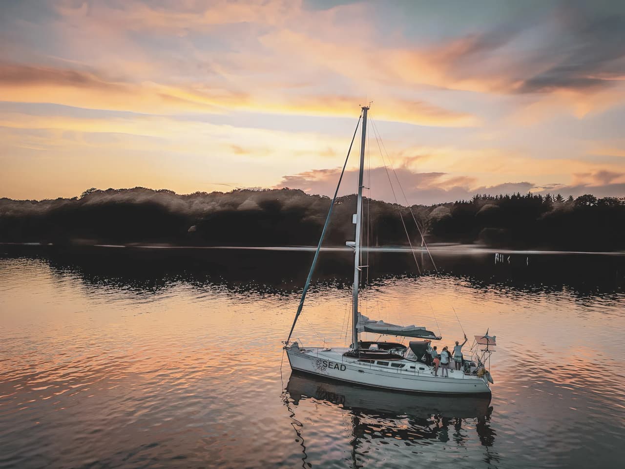 Voilier paisible se balançant sur l'eau calme, baigné par un coucher de soleil enchanteur.