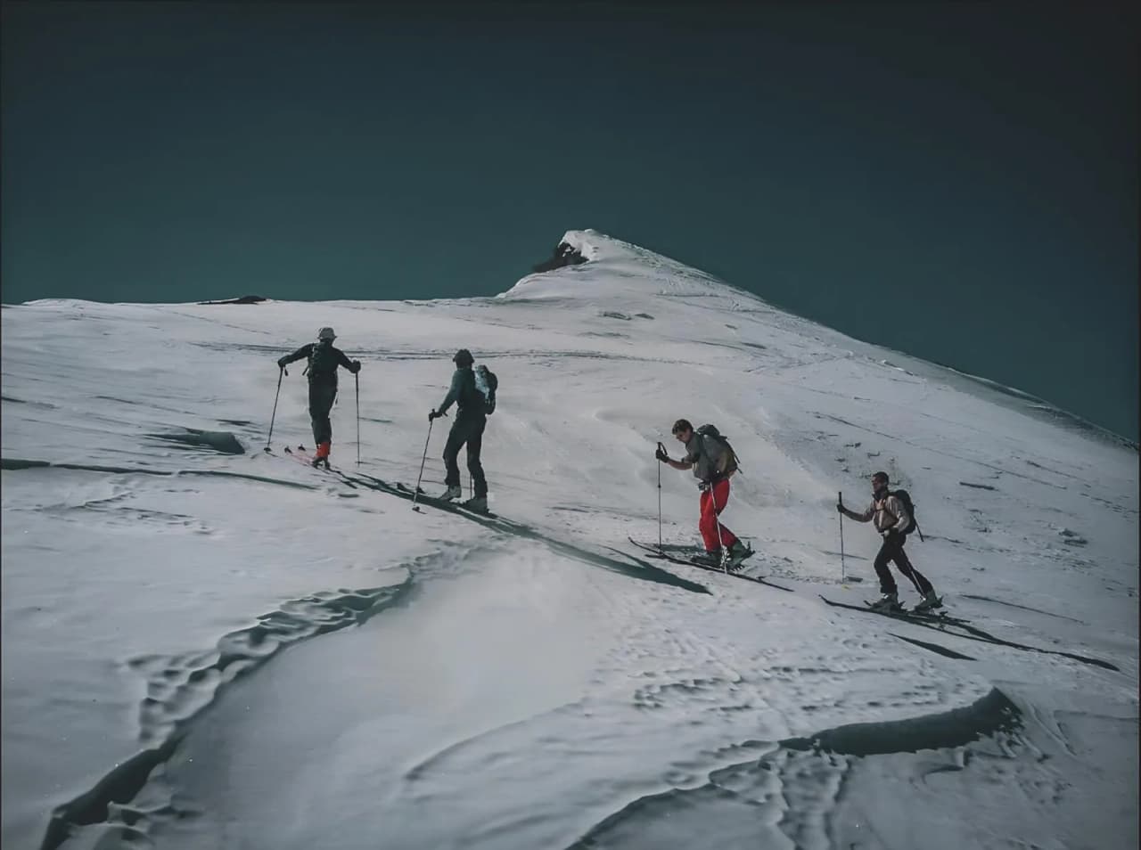 Groupe d'aventuriers en pleine ascension sur un glacier, entouré des paysages majestueux des Alpes.