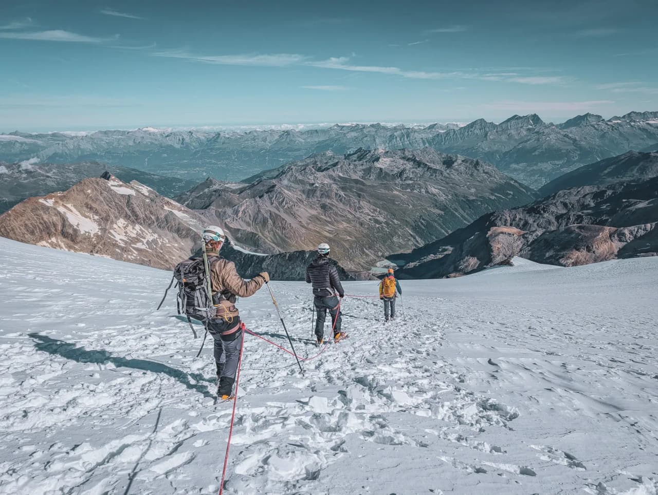 A group of climbers on a glacier, with majestic peaks in the background.