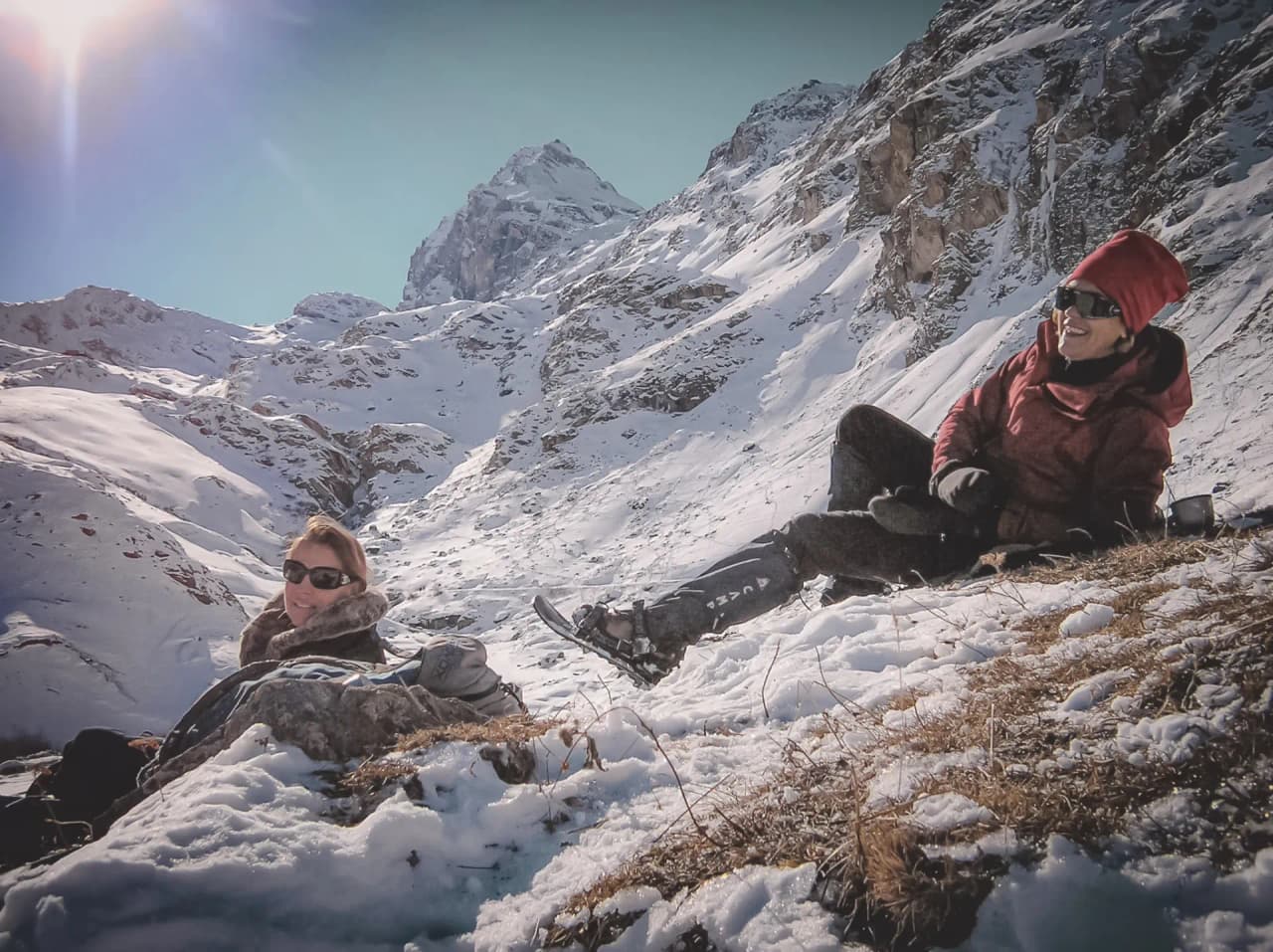 Two friends relax in a snow-covered Alpine landscape, surrounded by magnificent mountains.