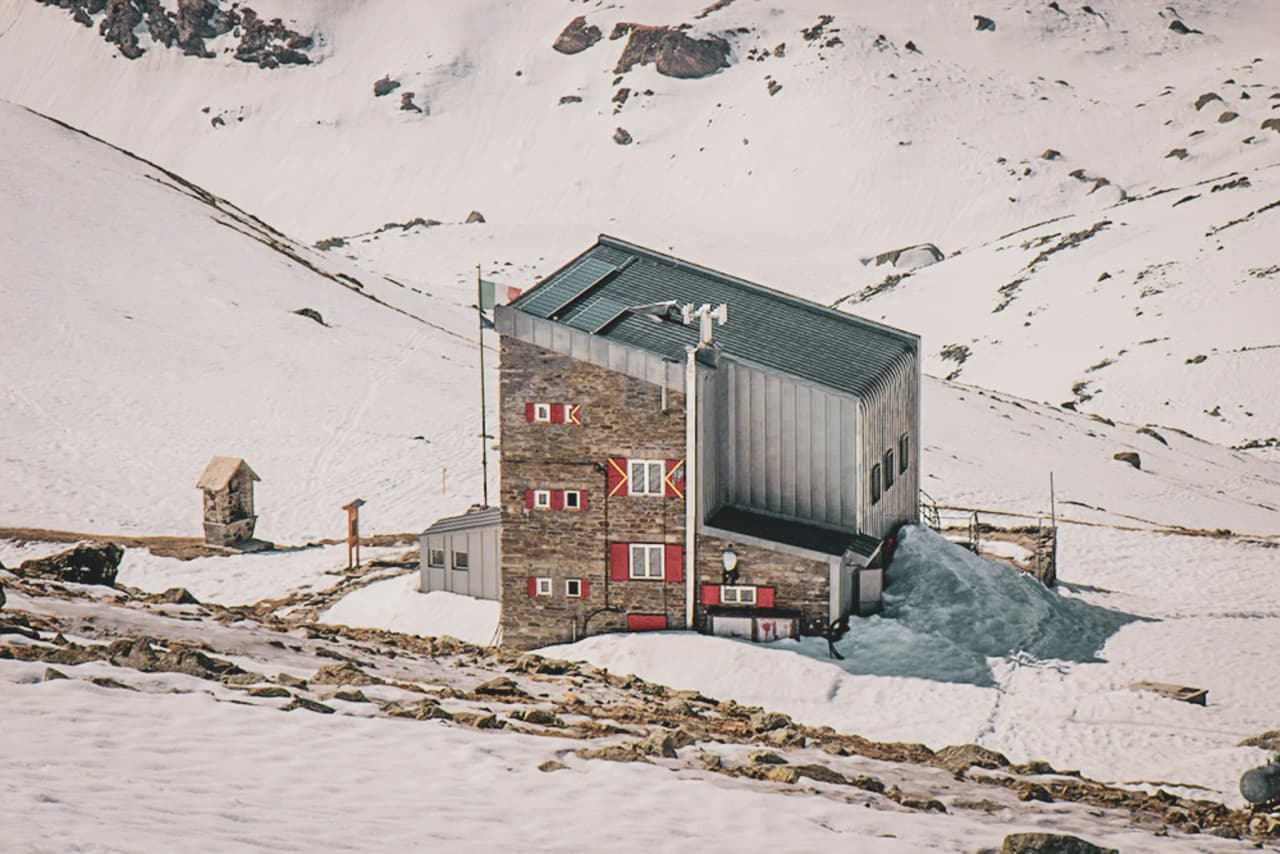 A modern mountain hut surrounded by snow and icy landscapes, perfect for an alpine adventure.