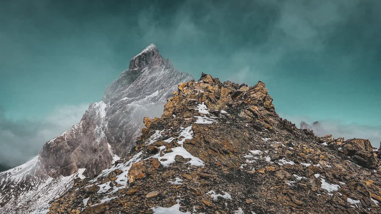 Un paysage alpin majestueux avec des sommets rocheux et un ciel turquoise, invitant à l'aventure.