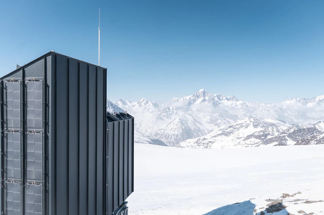 Une cabane moderne perchée sur un glacier, avec vue imprenable sur les Alpes enneigées.