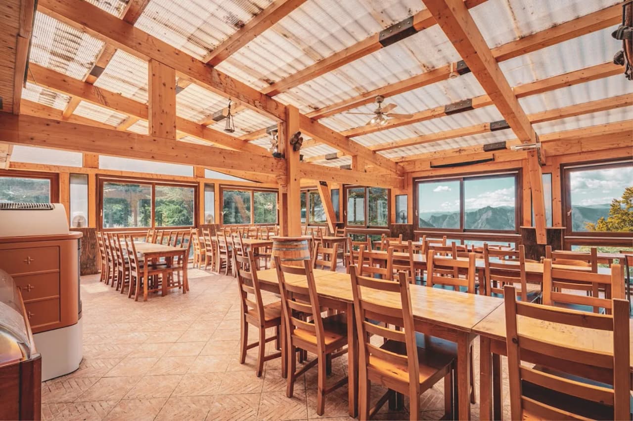 Salle à manger en bois chaleureuse, baignée de lumière, avec vue sur les montagnes du Mercantour.