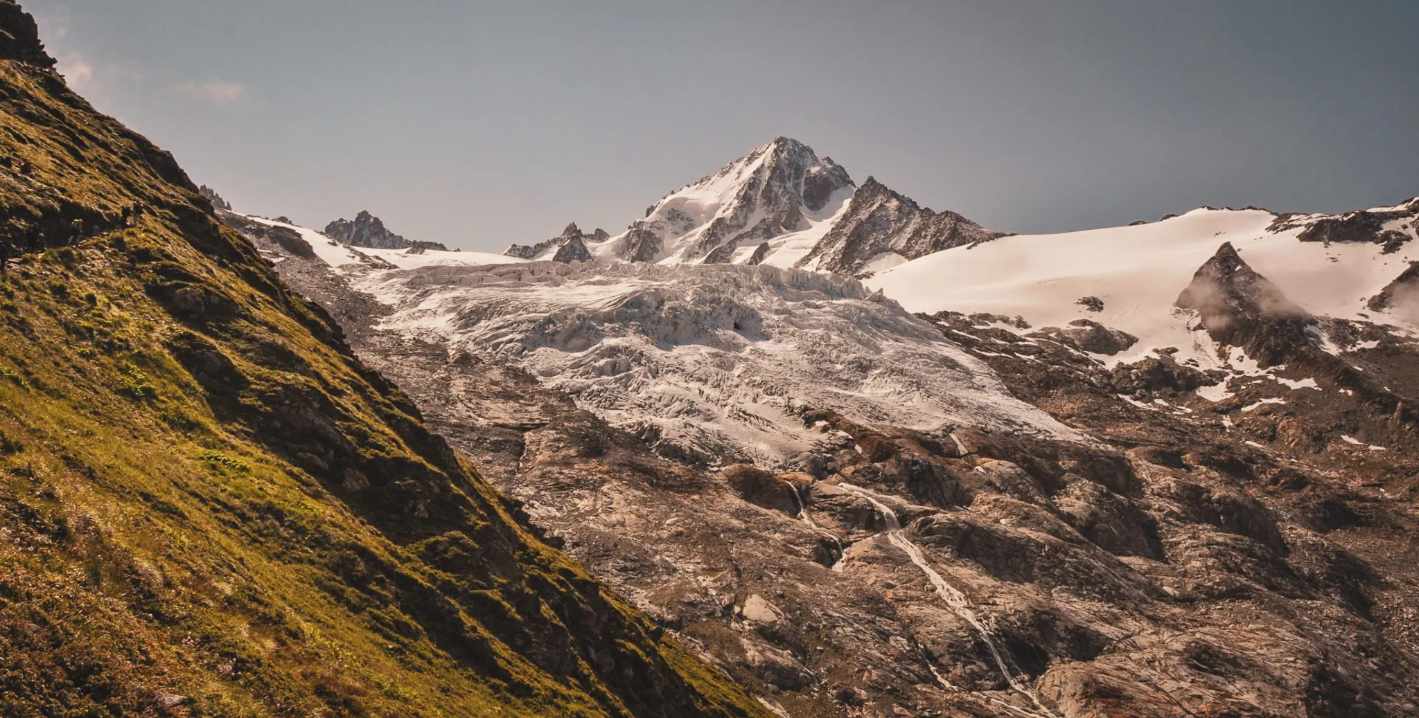 A vast Alpine panorama of snow-capped peaks and lush green slopes, an invitation to travel.