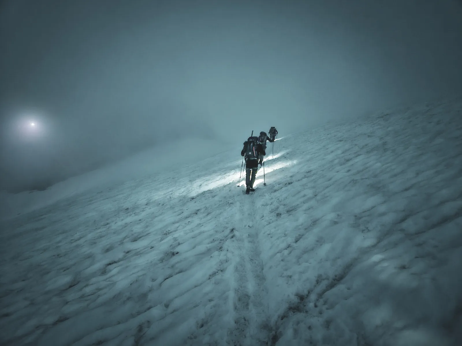 Mountaineers ascending a glacier through a mysterious fog, an atmosphere of adventure.