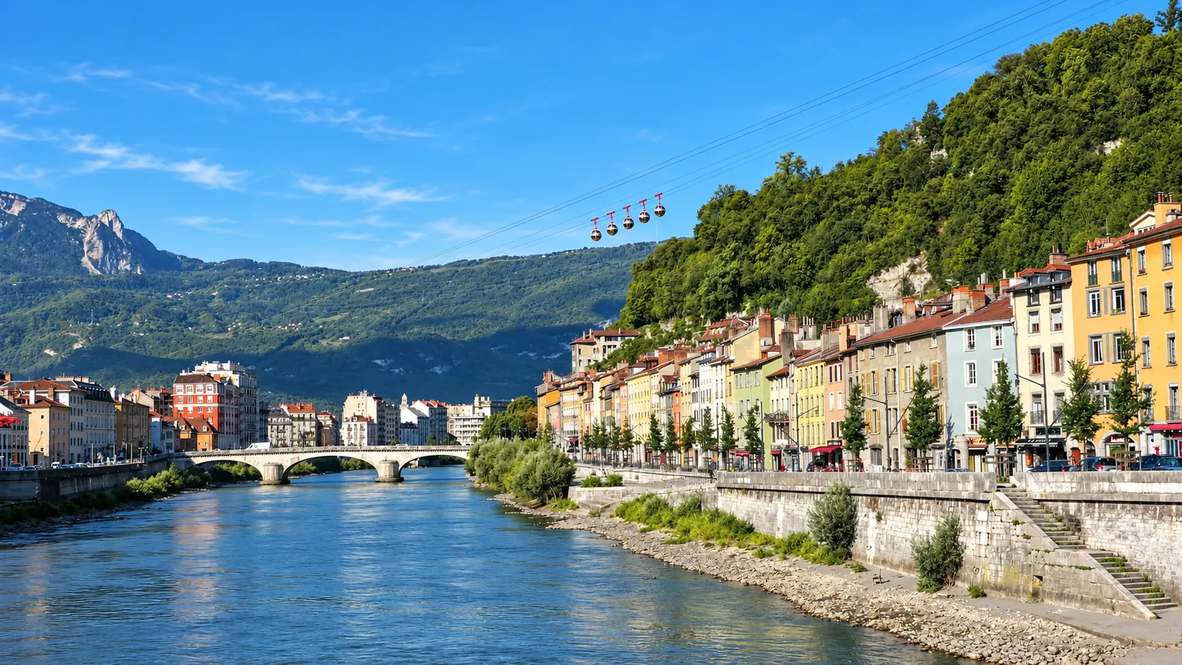 Une vue pittoresque de Grenoble, avec des maisons colorées le long de l'Isère et les montagnes en arrière-plan.