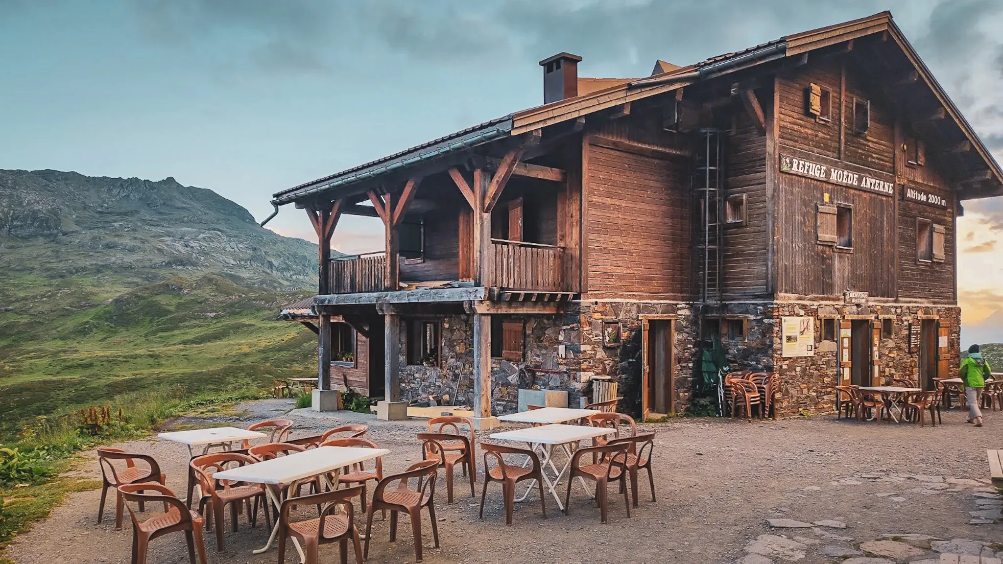 A cosy alpine mountain hut surrounded by lush green mountains, perfect for a wilderness adventure.