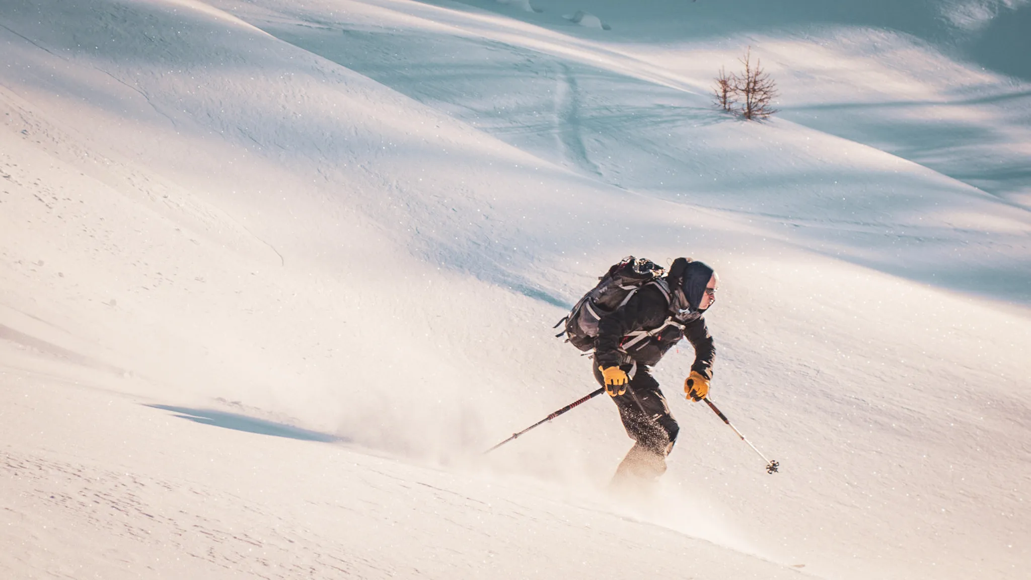 Un skieur glisse sur des pentes enneigées du Queyras, sous un ciel éclatant, invitant à l'aventure.