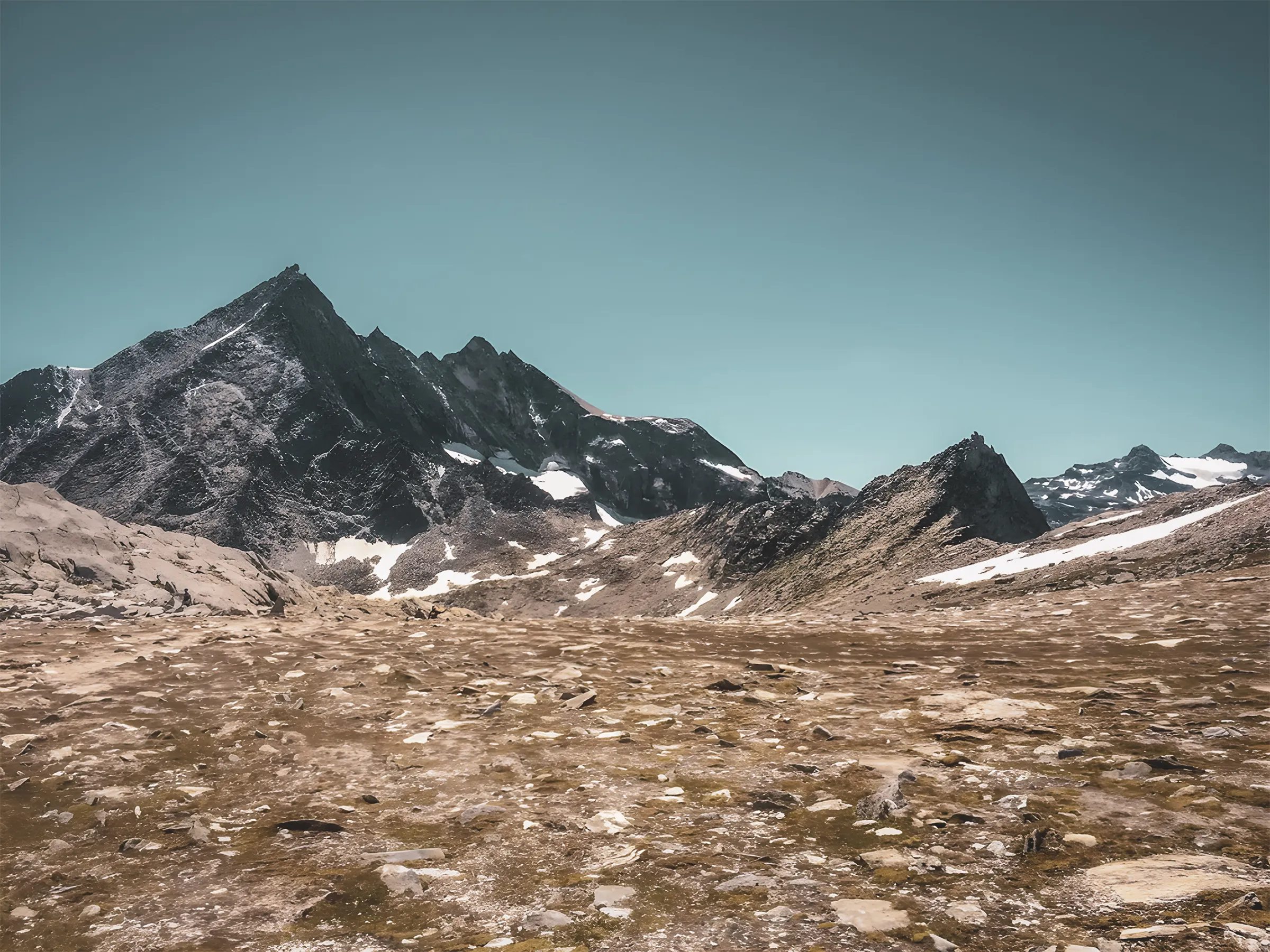 Majestic Alpine scenery with craggy peaks and vast meadows under a clear blue sky.
