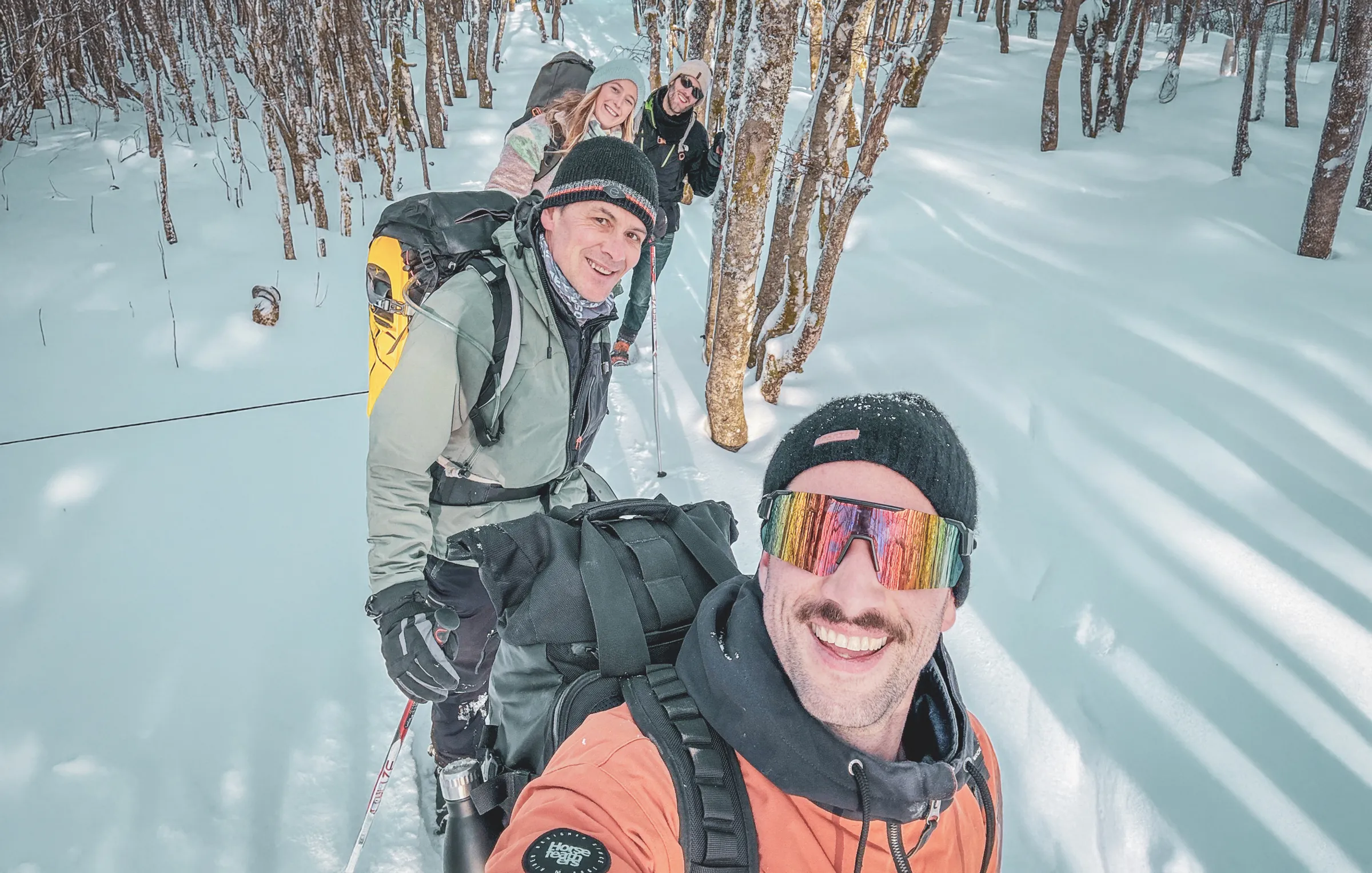 Groupe d'amis en raquettes, souriants dans une forêt enneigée des Vosges. Aventure hivernale !