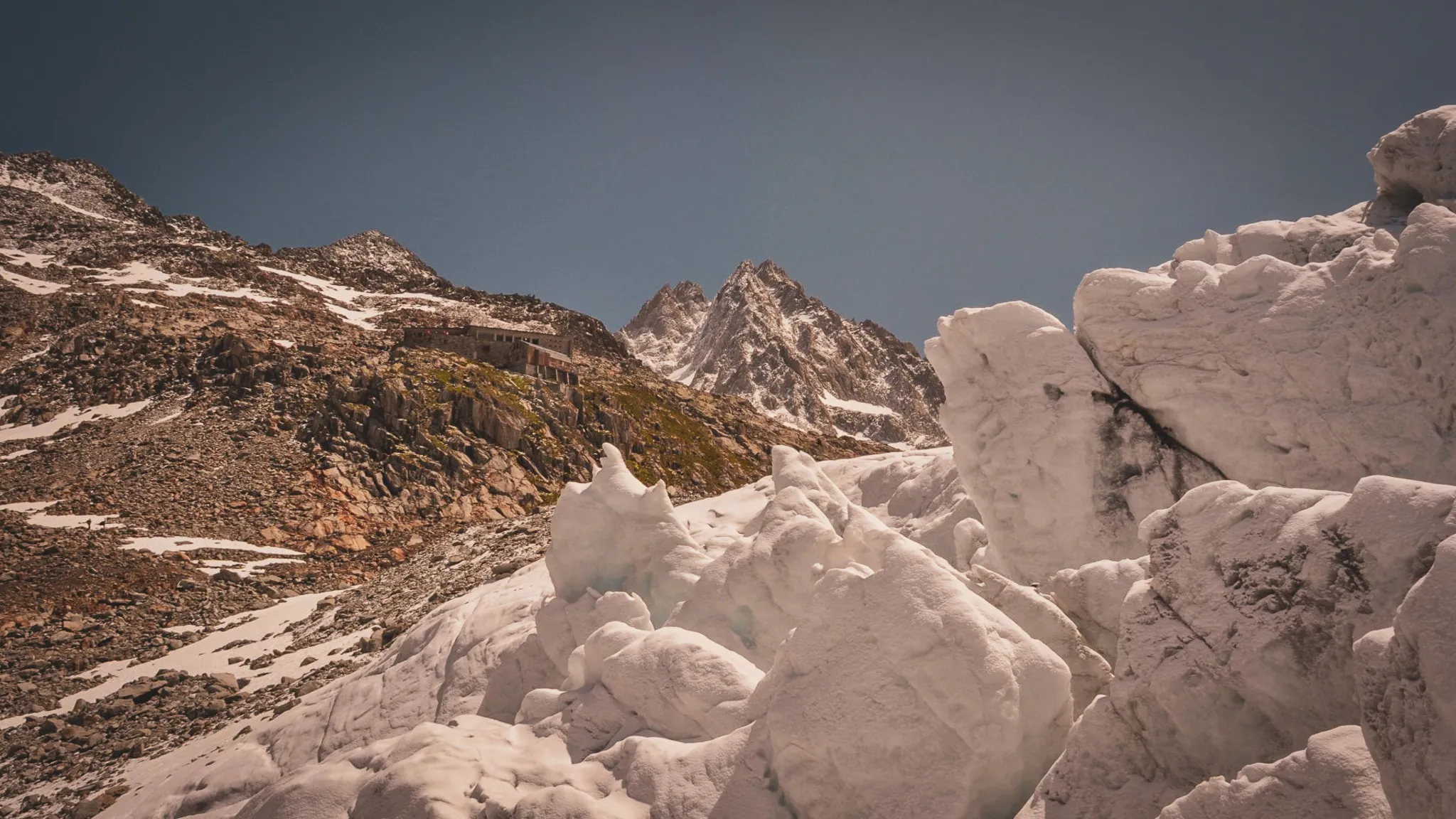 Majestic Alpine scenery, glistening glaciers under a blue sky, an invitation to adventure.