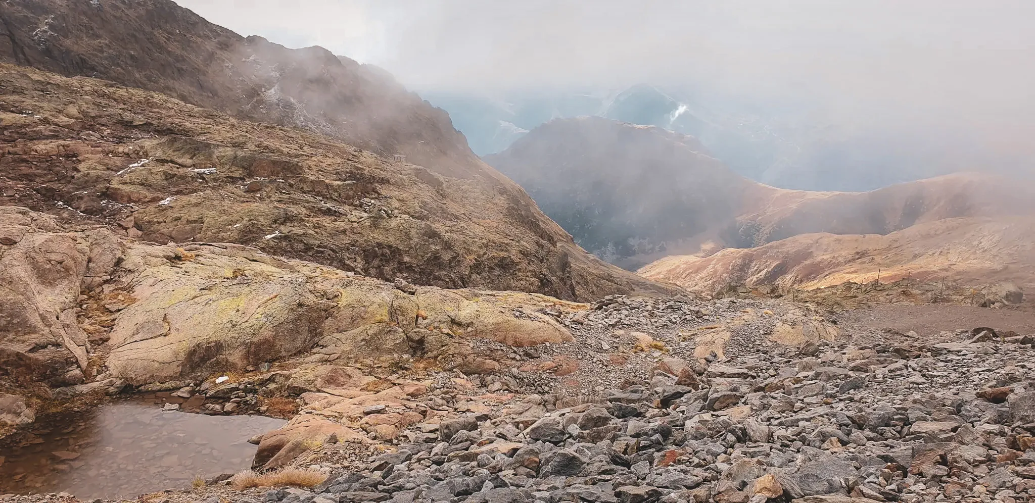 Un paysage de montagne impressionnant avec des rochers colorés, des vallées profondes et un ciel brumeux.