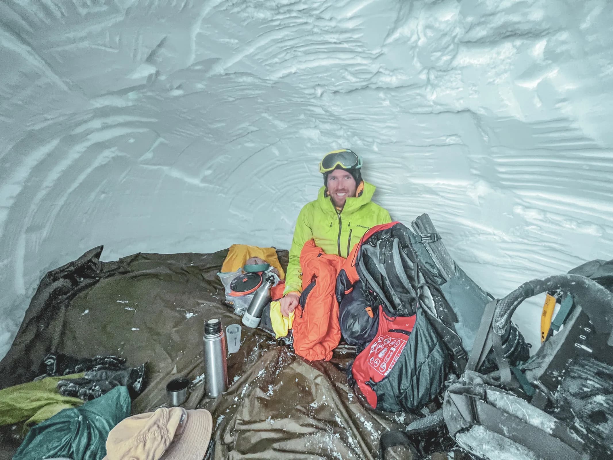 Un aventurier souriant dans un igloo, prêt pour une nuit magique face à la Meije.